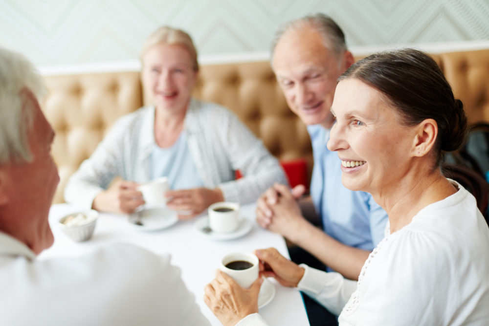 A group of seniors at a cafe having a cup of coffee and talking