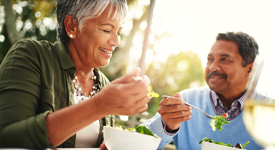 Elderly couple enjoys a salad meal outside