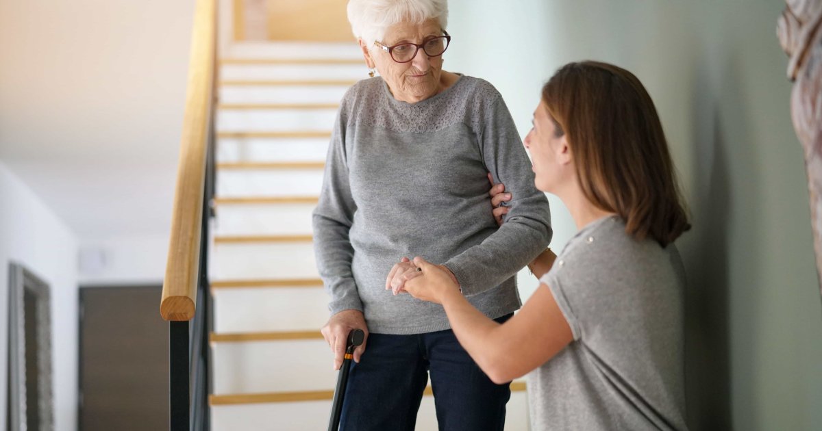Woman helping a senior down the stairs