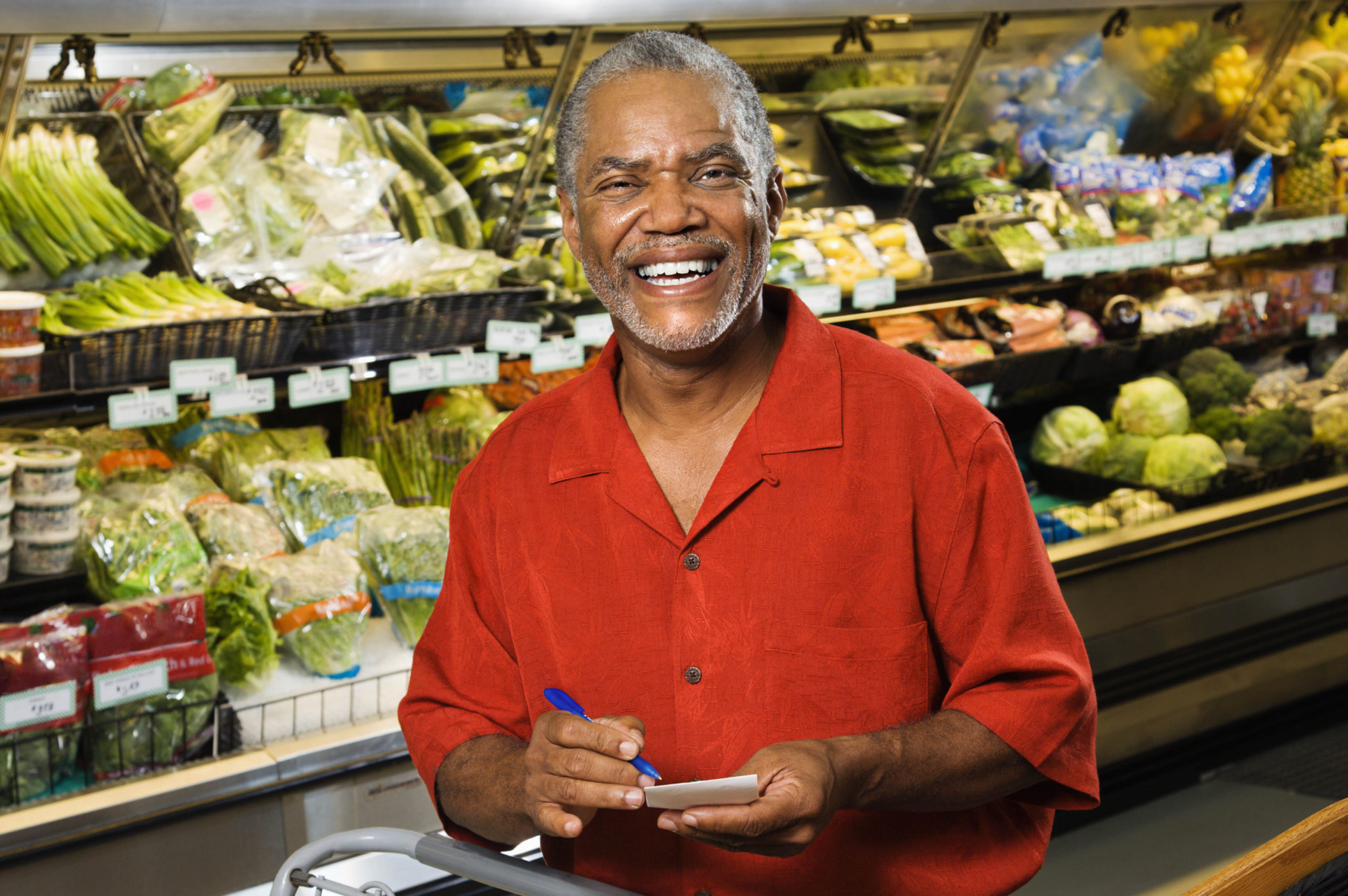 Older man smiling while picking fresh fruits and vegetables
