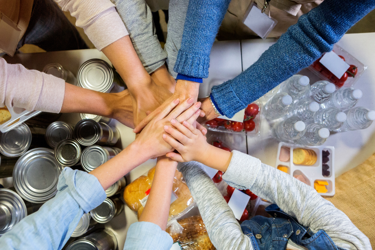 several hands held over abundance of food donations