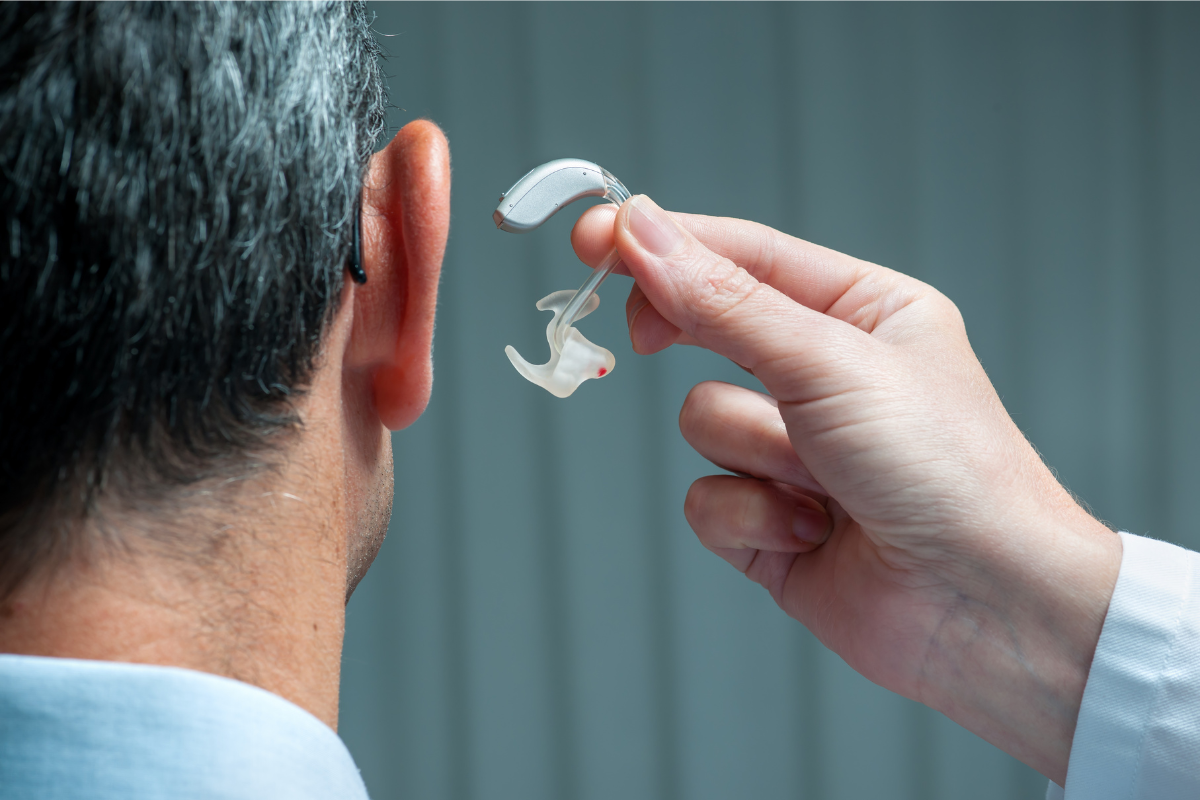 older adult receiving a new hearing aid